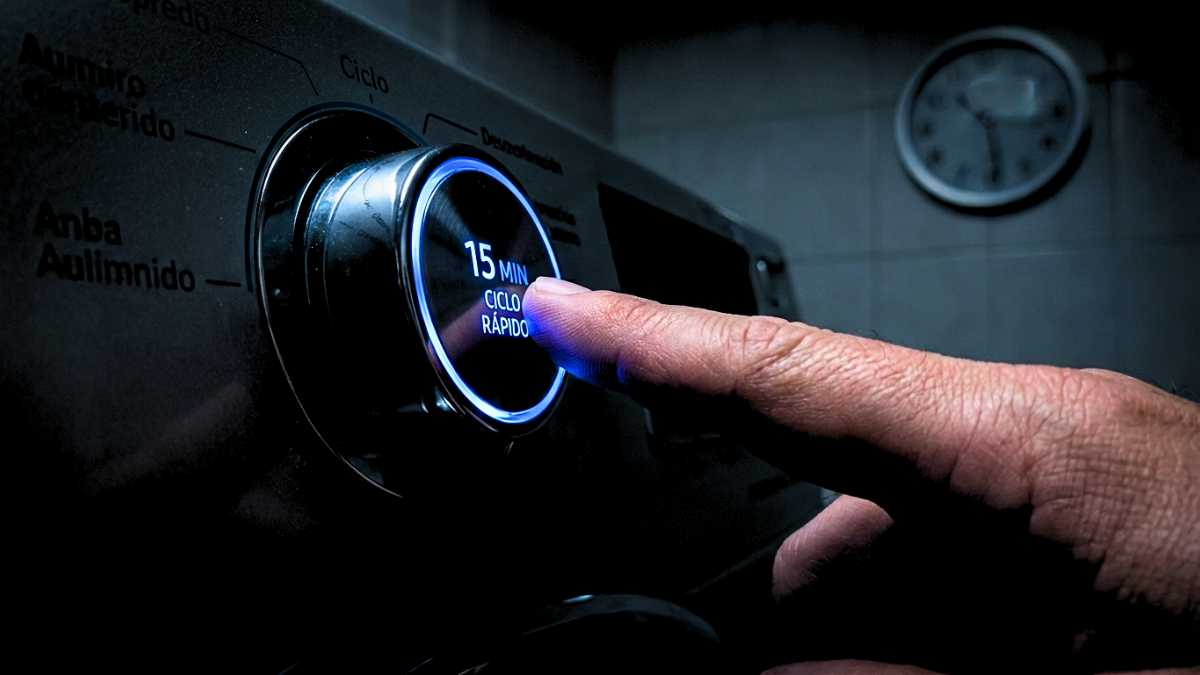 Close-up de dedo pressionando o botão de ciclo rápido de 15 minutos, o segredo de como economizar energia máquina de lavar.